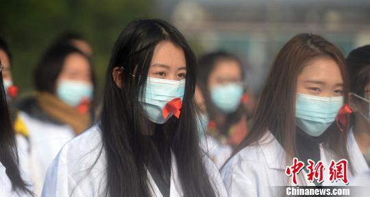 The picture shows college students wearing masks with red ribbons. Photo by Meng Delong